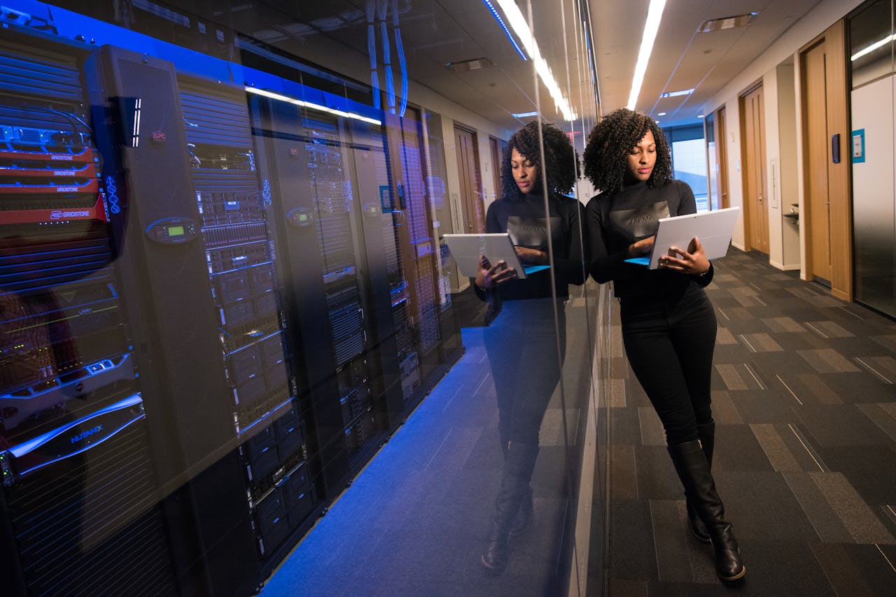 services-04 A woman using a laptop navigating a contemporary data center with mirrored servers.