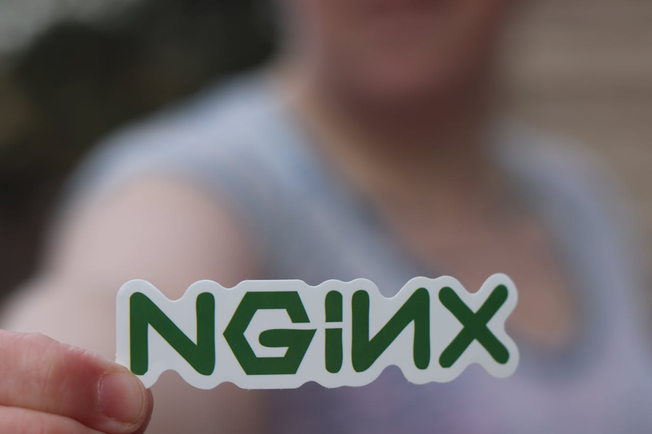 services-01 A close-up of a person holding an NGINX sticker with a blurred background.